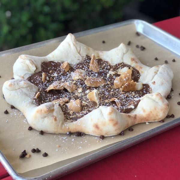 DeSano Pizzeria Napoletana's dessert pizza with chocolate, powdered sugar, and cookie crumbles on a tray.