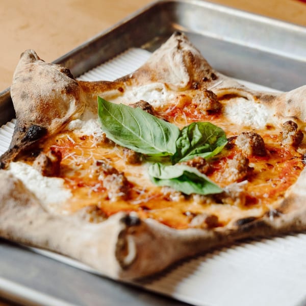 DeSano Pizzeria Napoletana's square pizza with sausage, ricotta, tomato sauce, and fresh basil on a metal tray.